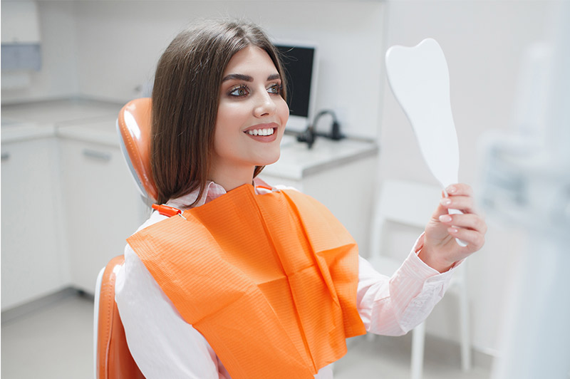 Very nice lady smiling looking into mirror from dental chair