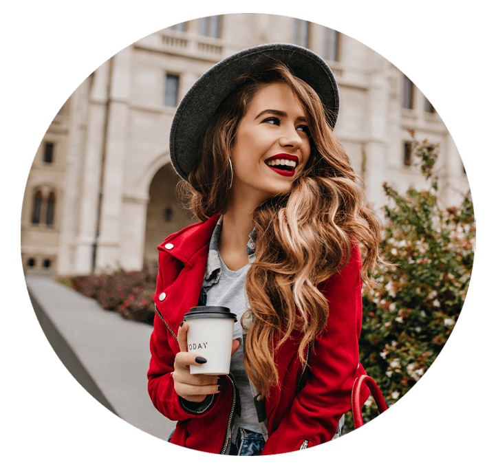 Very nice lady outside smiling hat and red coat holding coffee looking to the side