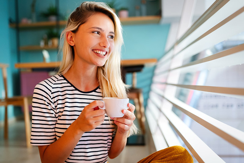 very nice lady with blonde hair smiling about to drink tea