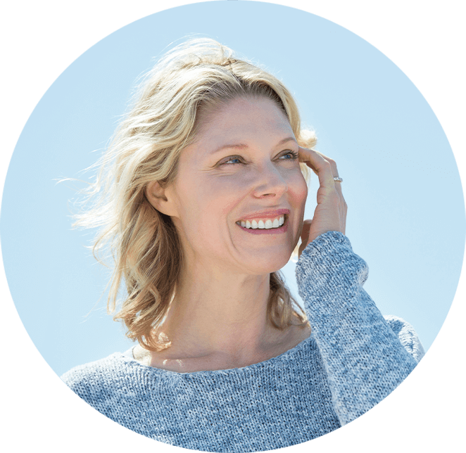 Very nice lady with blonde hair smiling looking away while touching her face